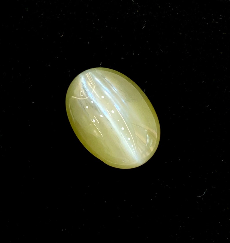 May include: A light green oval-shaped gemstone with a shimmering, iridescent effect.