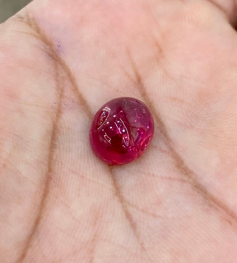 May include: A vibrant red gemstone cabochon, with a smooth, rounded surface and a slight shine.
