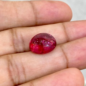 May include: A vibrant pink oval-shaped gemstone with a smooth, polished surface.