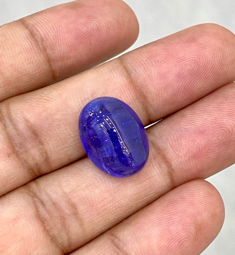 May include: A deep blue oval-shaped gemstone with a smooth, polished surface.