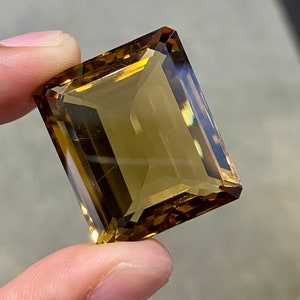 May include: A large, rectangular, faceted gemstone with a golden brown color.