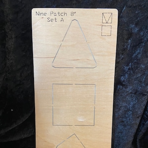 May include: A wooden quilting template with the text "Nine Patch 8" Set A." The template features cut-out shapes including a triangle, square, and a segmented triangle. The template is approximately 8 inches in length.