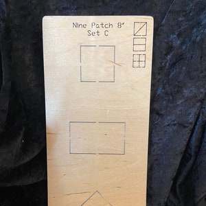 May include: A wooden quilting template with the text "Nine Patch 8" Set C." The template features cut-out shapes including squares, rectangles, and a triangle, along with small diagrams. The wood has a light brown color.