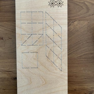 May include: A wooden die-cut template with the text "Scarlet EP-8P-SC-1 1/4" and several geometric designs. The designs include a square, a rectangle, and a series of angled lines. The template is made of light-colored wood.