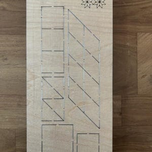 Puede incluir: Una plantilla de corte de madera con varias formas geométricas y el texto "Scarlet EP-8P-SC-1 1/2". Incluye cuadrados, rectángulos y líneas anguladas, además de un diseño floral decorativo. La madera es de color marrón claro.