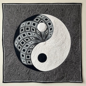Könnte beinhalten: Ein quadratischer Quilt mit einem Yin-und-Yang-Design in Schwarz, Weiß und Grau. Das zentrale Design hat ein detailliertes geometrisches Muster. Der Rand ist ein dunkleres Grau mit einer schwarz-weißen Umrandung, und der Quilt hat eine gesteppte Textur.