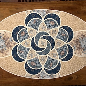 Peut inclure: Un chemin de table ovale avec un motif floral dans les tons bleus et beiges. Le chemin de table présente un design géométrique avec des lignes courbes et un motif central.