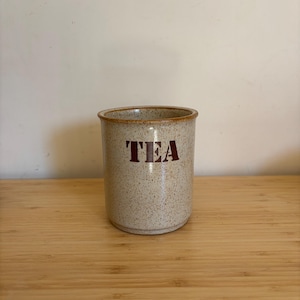 Könnte beinhalten: Eine weiße Keramiktasse mit schwarzem Henkel und dem Text "But First, Coffee" in fetter, schwarzer Schrift. Die Tasse steht auf einer weißen Oberfläche und zeigt ihr schlichtes Design.