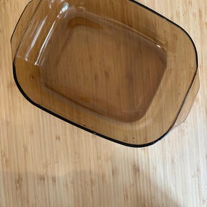 Könnte beinhalten: Eine rechteckige Backform aus braunem Glas. Die Form hat eine glatte, klare Oberfläche und abgerundete Kanten.