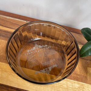 May include: A brown glass baking dish with a recipe for chocolate cake etched into the bottom. The recipe includes ingredients such as flour, sugar, eggs, and cocoa powder.