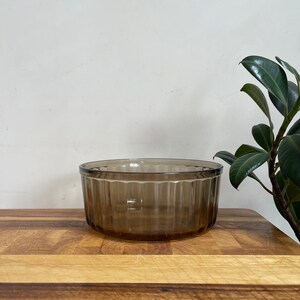 May include: A brown glass bowl with vertical ridges. The bowl is sitting on a wooden surface.