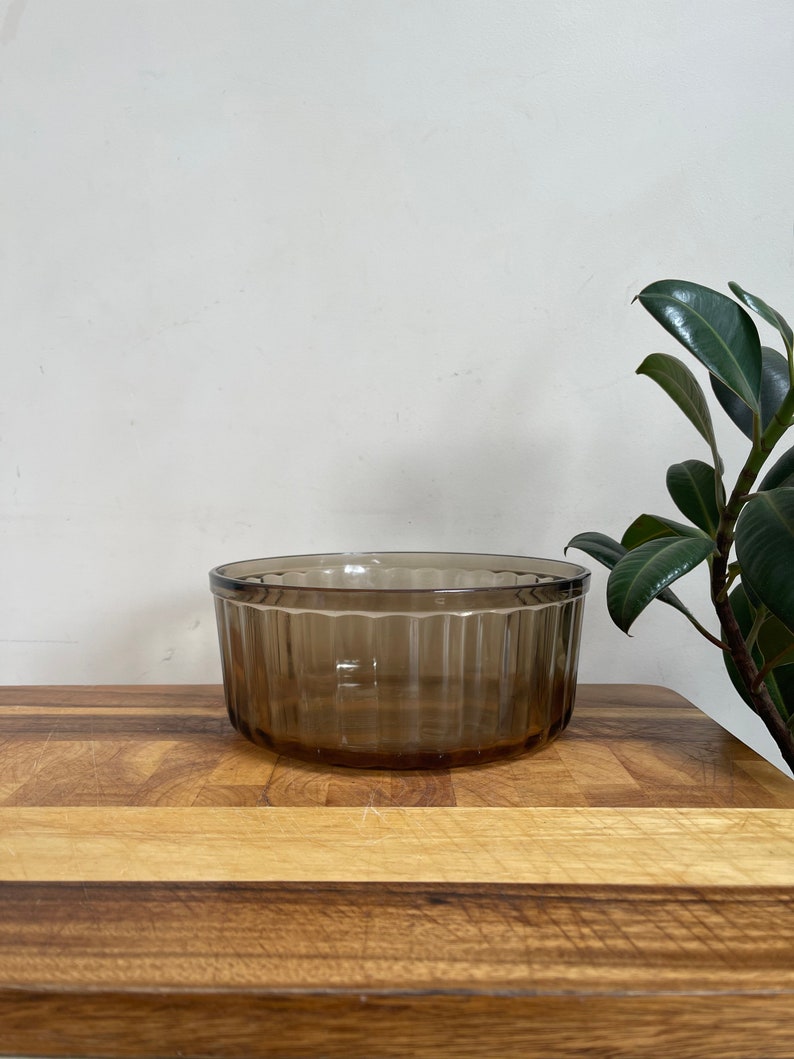 May include: A brown glass bowl with vertical ridges. The bowl is sitting on a wooden surface.