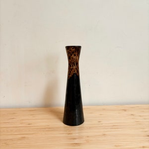 May include: A black and brown wooden vase with a flared top and a narrow base.