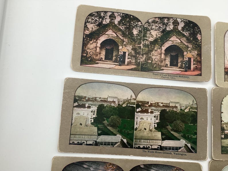 May include: Vintage stereoscopic cards featuring historical landmarks. One card depicts the Tomb of President McKinley in Canton, Ohio. Another shows the White House Grounds in Washington, D.C. The cards have a sepia tone.