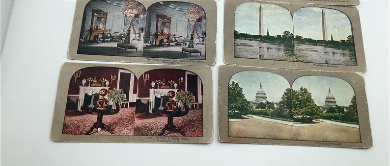 May include: A collection of vintage stereoscopic cards featuring historical scenes. The cards depict interior views of rooms, the Washington Monument, and the U.S. Capitol building. The cards have a sepia tone and are mounted on cardboard.