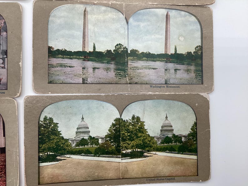 May include: Vintage stereoscopic cards featuring the Washington Monument and the United States Capitol. The cards have a sepia tone and depict the landmarks with trees and water. The text "Washington Monument" and "United States Capitol" are visible.