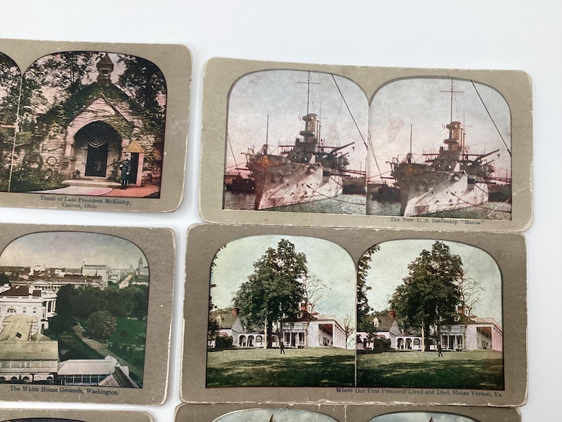 May include: A collection of vintage stereoview cards featuring historical landmarks and scenes. The cards depict the Tomb of President McKinley, the U.S. Battleship Maine, the White House Grounds, and Mount Vernon. The cards have a sepia tone and are in good condition.