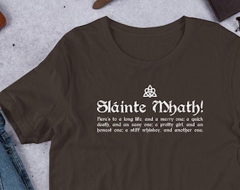May include: A brown t-shirt with a white graphic print of a Celtic knot and the text "Sláinte Mhath!"  The text below the graphic reads "Here's to a long life, and a merry one; a quick death, and an easy one; a pretty girl, and an honest one; a stiff whiskey, and another one."