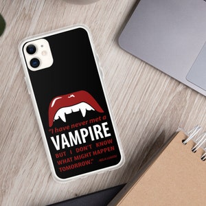 May include: A black phone case with a clear back. The case features a red vampire mouth with fangs and a white quote that reads "I have never met a VAMPIRE BUT I DON'T KNOW WHAT MIGHT HAPPEN TOMORROW." The quote is attributed to "ABLA LUGOR".
