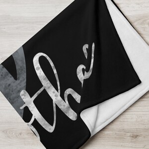 May include: Black fleece throw blanket with the word "Love" written in white with a speckled texture.