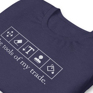 May include: A navy blue t-shirt with white text that reads "These tools of my trade." The text is accompanied by five white icons representing common design tools.