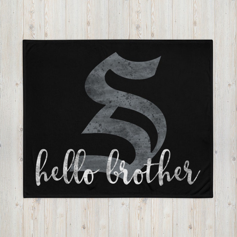 May include: Black fleece blanket with a large, silver, stylized letter "S" and the text "hello brother" in a white, cursive font.