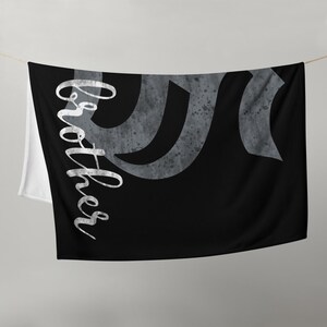 May include: Black and white beach towel with a gray abstract design and the word "Brother" written in white cursive script.