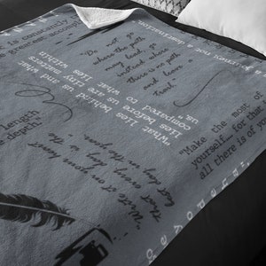 May include: A gray fleece throw blanket with inspirational quotes printed on it. The quotes include "Do not go where the path may lead, go instead where there is no path and leave a trail." and "Make the most of yourself... for that is all there is of you."