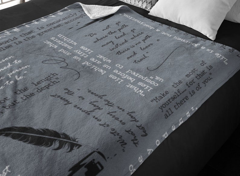 May include: A gray fleece throw blanket with inspirational quotes printed on it. The quotes include "Do not go where the path may lead, go instead where there is no path and leave a trail." and "Make the most of yourself... for that is all there is of you."