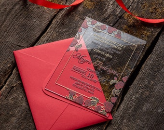 May include: A red envelope with a clear acrylic invitation card featuring a floral design and gold lettering. The invitation card reads "Roberto Rodriguez y Melissa Gonzalez Cordialmente los invitan a celebrar sus Quince Años" and "Meyra Rodriguez Viernes 10 Febrero 2024 a las 4:00 pm Forever Reception Hall 488 W. 17th Ave. Hialeah, FL 33010".
