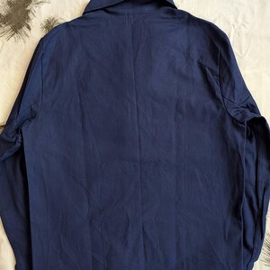 May include: A navy blue long-sleeved shirt with a collar and buttoned cuffs. The shirt is made of a smooth fabric and has a classic design. The back of the shirt is visible, showing the tailored fit.