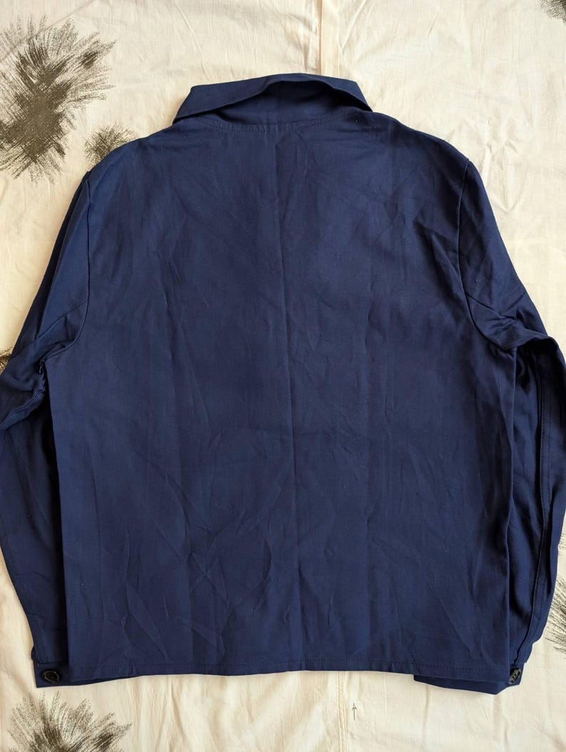 May include: A navy blue long-sleeved shirt with a collar and buttoned cuffs. The shirt is made of a smooth fabric and has a classic design. The back of the shirt is visible, showing the tailored fit.