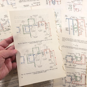 May include: A hand holds a page with a detailed circuit diagram, featuring blue, green, and red lines. Other pages with similar diagrams are scattered around. The diagrams appear to be from an older technical manual.