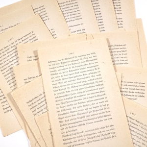 May include: A pile of old, yellowed, and slightly damaged paper pages with handwritten text in German. The pages are scattered and overlapping, with some edges torn. The text is in a cursive script and appears to be from a book or manuscript.