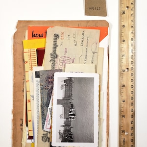 May include: A collection of vintage ephemera, including receipts, a black and white photograph, and a small tag with the number "001412". A wooden ruler, 12 inches long, is placed next to the items.