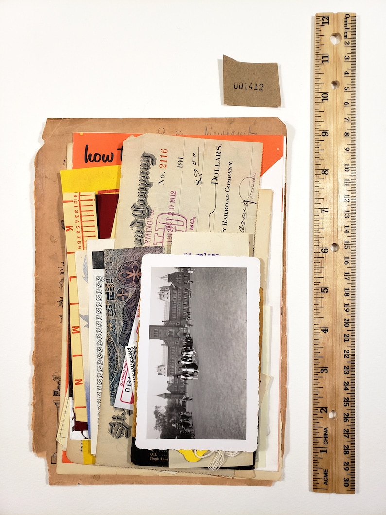 May include: A collection of vintage ephemera, including receipts, a black and white photograph, and a small tag with the number "001412". A wooden ruler, 12 inches long, is placed next to the items.