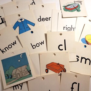 以下が含まれることがあります： イラストと単語が書かれた、ヴィンテージのフラッシュカードのコレクション。青いコート、赤いワゴン、家、ボートの画像が特徴です。「know」、「bow」、「deer」、「right」などの単語が含まれています。各カードの上部には穴が開いています。