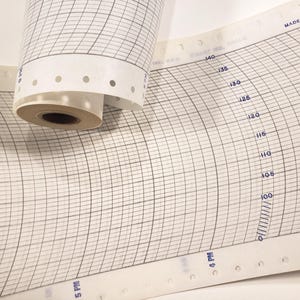 May include: A roll of white graph paper with a grid pattern and numbers printed on the side. The paper is rolled up and has a hole punch along the edge. The paper is labeled "MADE IN U.S.A.".