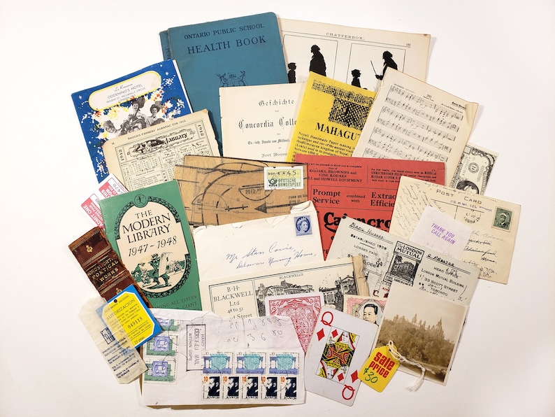 May include: A collection of vintage ephemera, including books, postcards, stamps, and documents. The items are arranged on a white surface, featuring a variety of colors and textures. Notable items include a blue health book and a playing card.