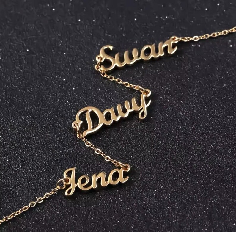 May include: Gold necklace with three names, "Swant", "Davy", and "Jena", spelled out in cursive.