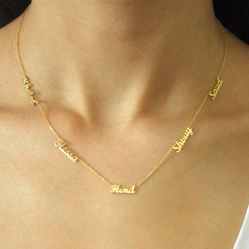 May include: A gold chain necklace with five personalized name tags. The names on the tags are "Hessa", "Hend", "Shauqi", "Saud", and "Wheedat".