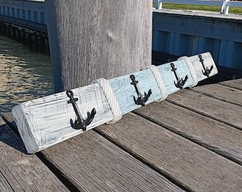 Peut inclure: Un porte-manteau en bois sur le thème nautique. Le porte-manteau est peint en blanc et bleu et comporte quatre crochets d'ancre en métal noir. Le porte-manteau est monté sur une surface en bois.