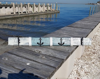 Peut inclure: Un porte-manteau mural en bois sur le thème nautique. Le porte-manteau est peint dans des tons de bleu et de blanc et comporte trois crochets d'ancre noirs. Le porte-manteau est fait de bois de récupération et a un aspect rustique.