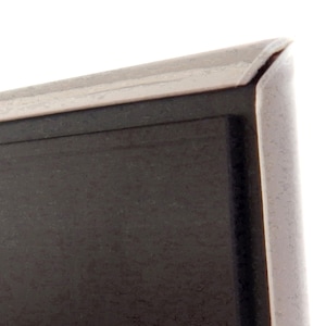 Pode incluir: Close-up de uma moldura cinza escura com uma borda prateada. A moldura tem um design simples e moderno e uma superf&iacute;cie ligeiramente texturizada. O canto da moldura &eacute; vis&iacute;vel contra um fundo branco.