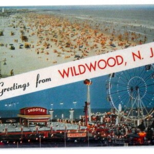 May include: A vintage postcard depicting a beach scene with a crowded boardwalk and a Ferris wheel. The postcard reads "Greetings from Wildwood, N.J."