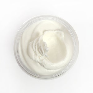 May include: A white, creamy substance in a clear jar. The substance is thick and has a smooth texture.