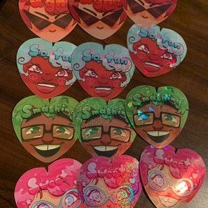 Puede incluir: Un conjunto de diez pegatinas en forma de corazón que presentan varios personajes de dibujos animados con diferentes expresiones. Las pegatinas tienen un acabado brillante y están impresas con colores vibrantes. Los personajes incluyen una persona con gafas de sol, una persona con cabello verde y gafas, y una persona con cabello rosa y gafas. Las pegatinas tienen texto en ellas, incluyendo "Ugh", "So Fun" y "Smashing".