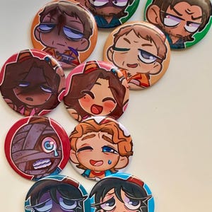Może przedstawiać: Zestaw 10 okrągłych pinów w kształcie guzików przedstawiających postacie z kreskówek z różnymi wyrażeniami. Piny są kolorowe i mają błyszczące wykończenie.