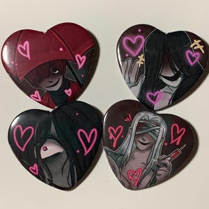 Puede incluir: Cuatro botones en forma de corazón con diferentes personajes del videojuego "Doki Doki Literature Club!". Cada botón presenta un personaje con corazones rosas dibujados a su alrededor.