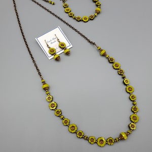 K&ouml;nnte beinhalten: Ein Set aus gelben, blumenf&ouml;rmigen tschechischen Glasperlen. Das Set enth&auml;lt eine Halskette, ein Armband und Ohrringe. Die Perlen sind auf einer Bronzekette aufgef&auml;delt.